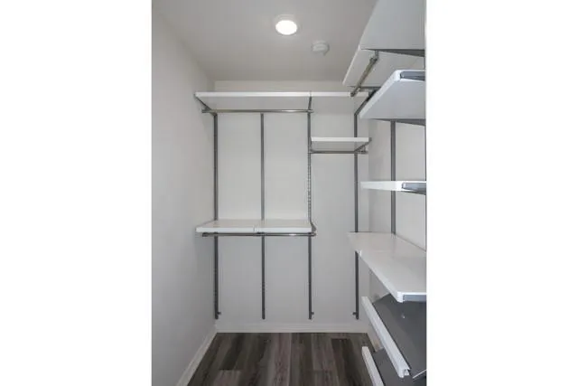 an empty room with wooden floor chandelier and windows