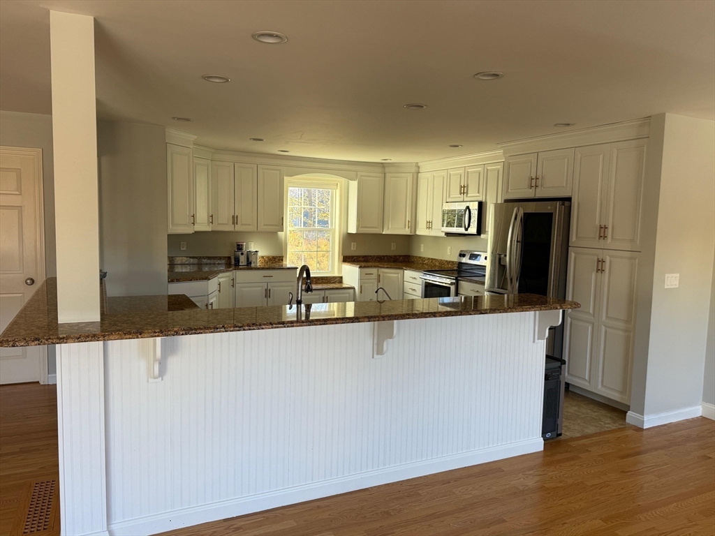 15 Spencer Street Methuen, MA 01844 - Photo 21 of 25 a kitchen with stainless steel appliances granite countertop a stove a sink a refrigerator a microwave oven and a cabinets with wooden floor