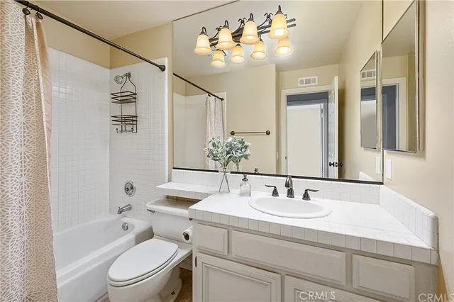 a bathroom with a sink a toilet a mirror a vanity and bathtub