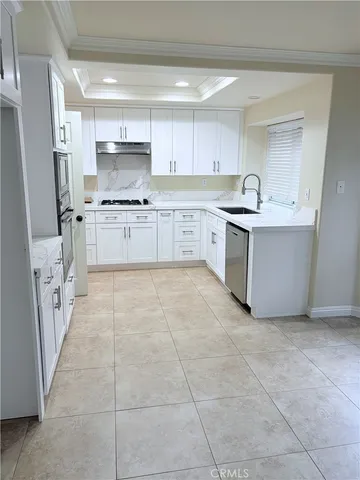 a large kitchen with a stove top oven a sink a refrigerator and white cabinets
