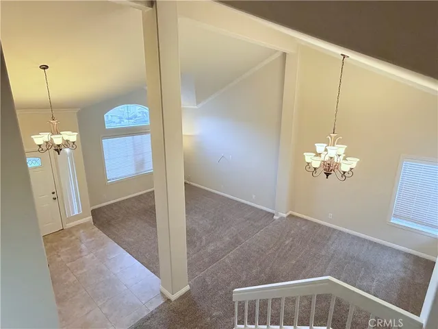 a view of a room with a chandelier fan and wooden floor