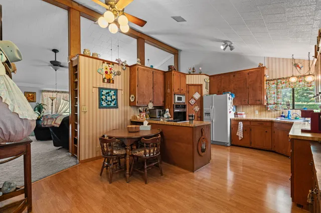 a kitchen with stainless steel appliances a stove a refrigerator a dining table and chairs with wooden floor