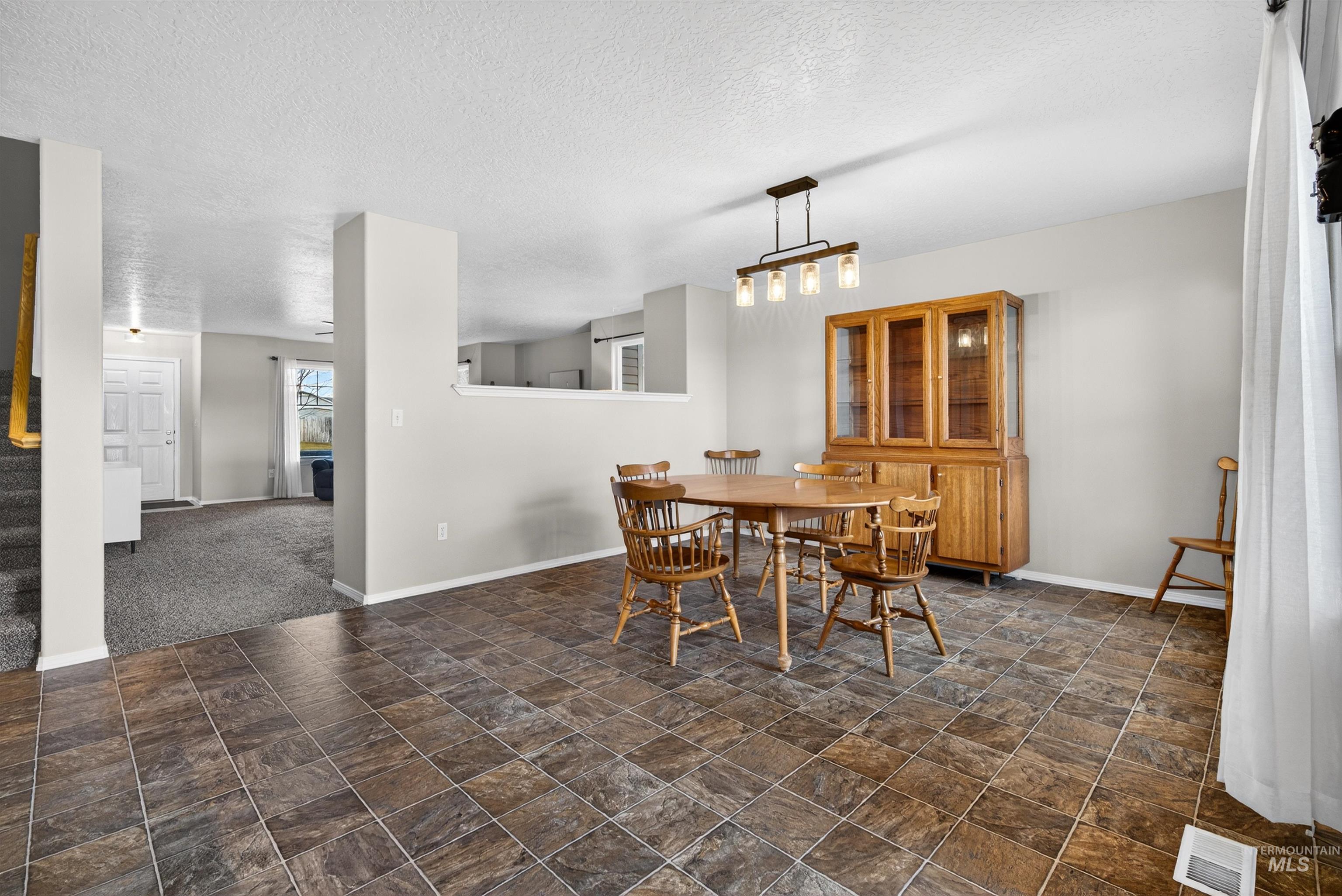 5414 Barkley Way Caldwell, ID 83607 - Photo 15 of 50 Dining room featuring stone finish flooring, a textured ceiling, and dark colored carpet