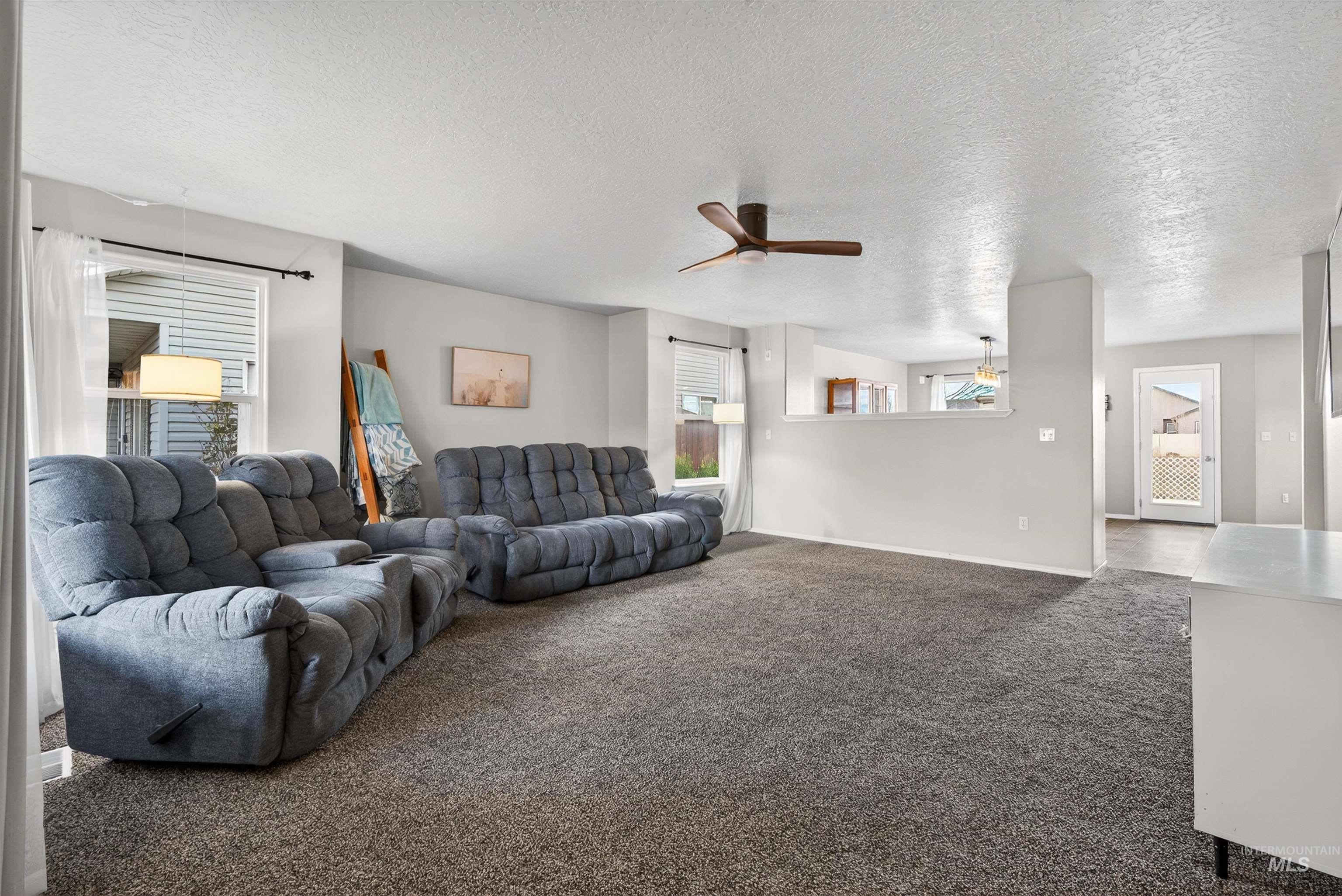 5414 Barkley Way Caldwell, ID 83607 - Photo 5 of 50 Living room featuring dark carpet, a ceiling fan, and a textured ceiling