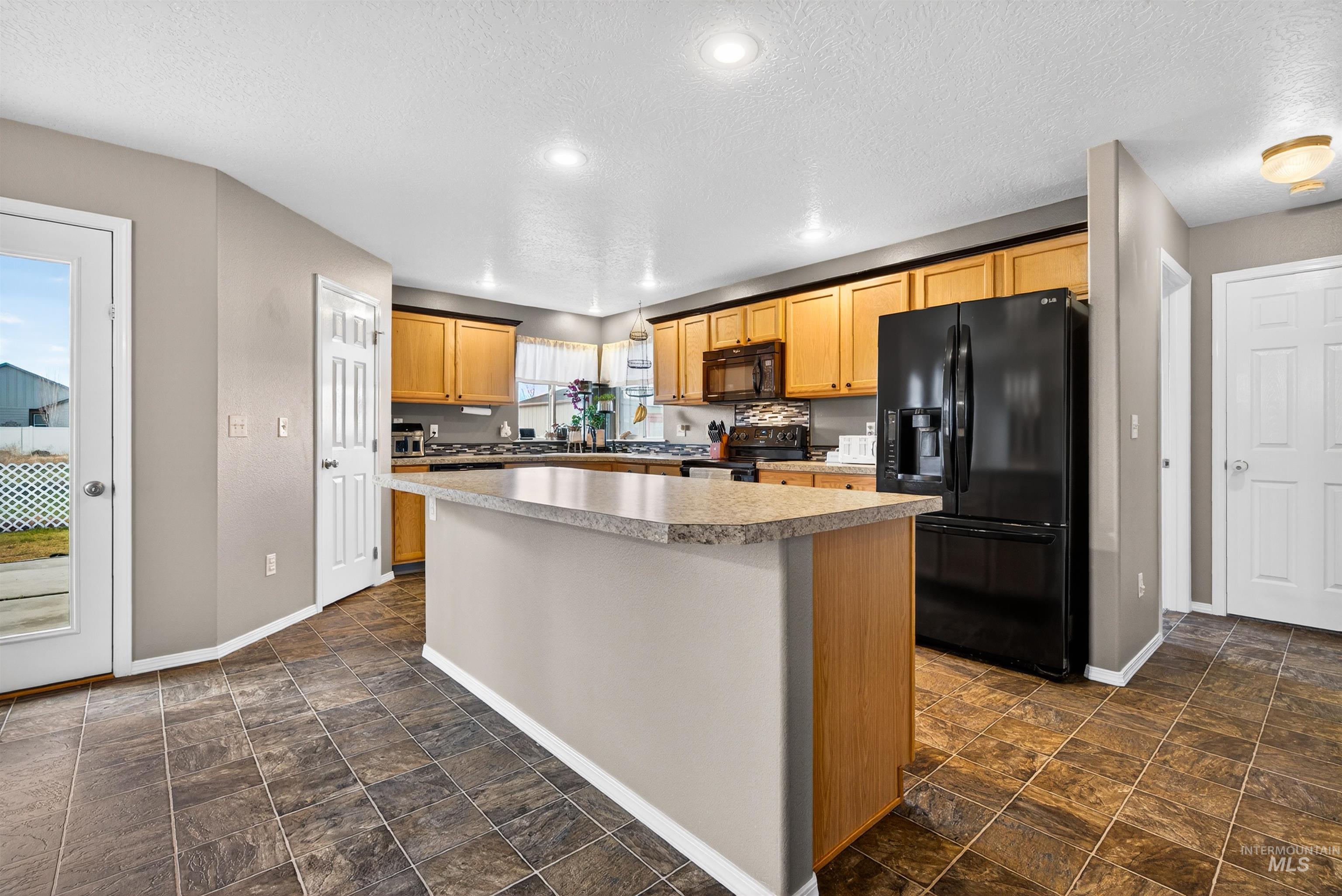 5414 Barkley Way Caldwell, ID 83607 - Photo 7 of 50 Kitchen featuring black appliances, stone finish flooring, a center island, light countertops, and recessed lighting