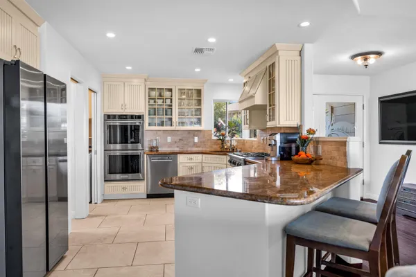 a kitchen with stainless steel appliances granite countertop a stove refrigerator and a view of living room