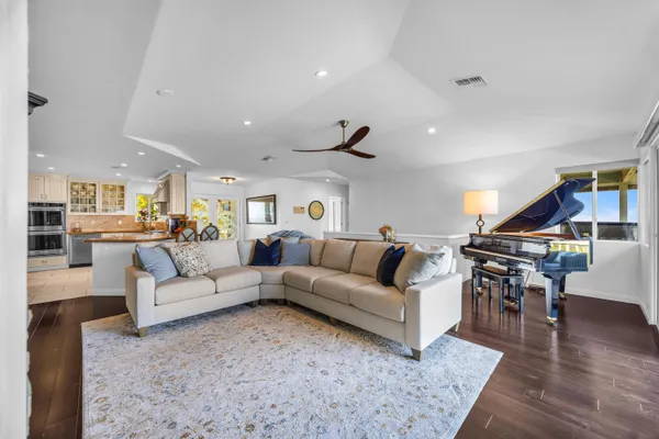 a living room with furniture kitchen view and a wooden floor