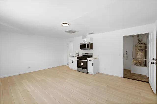 a large white kitchen with granite countertop a sink and dishwasher a stove with wooden floor