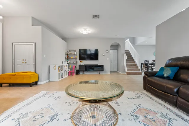 a living room with furniture kitchen view and a wooden floor