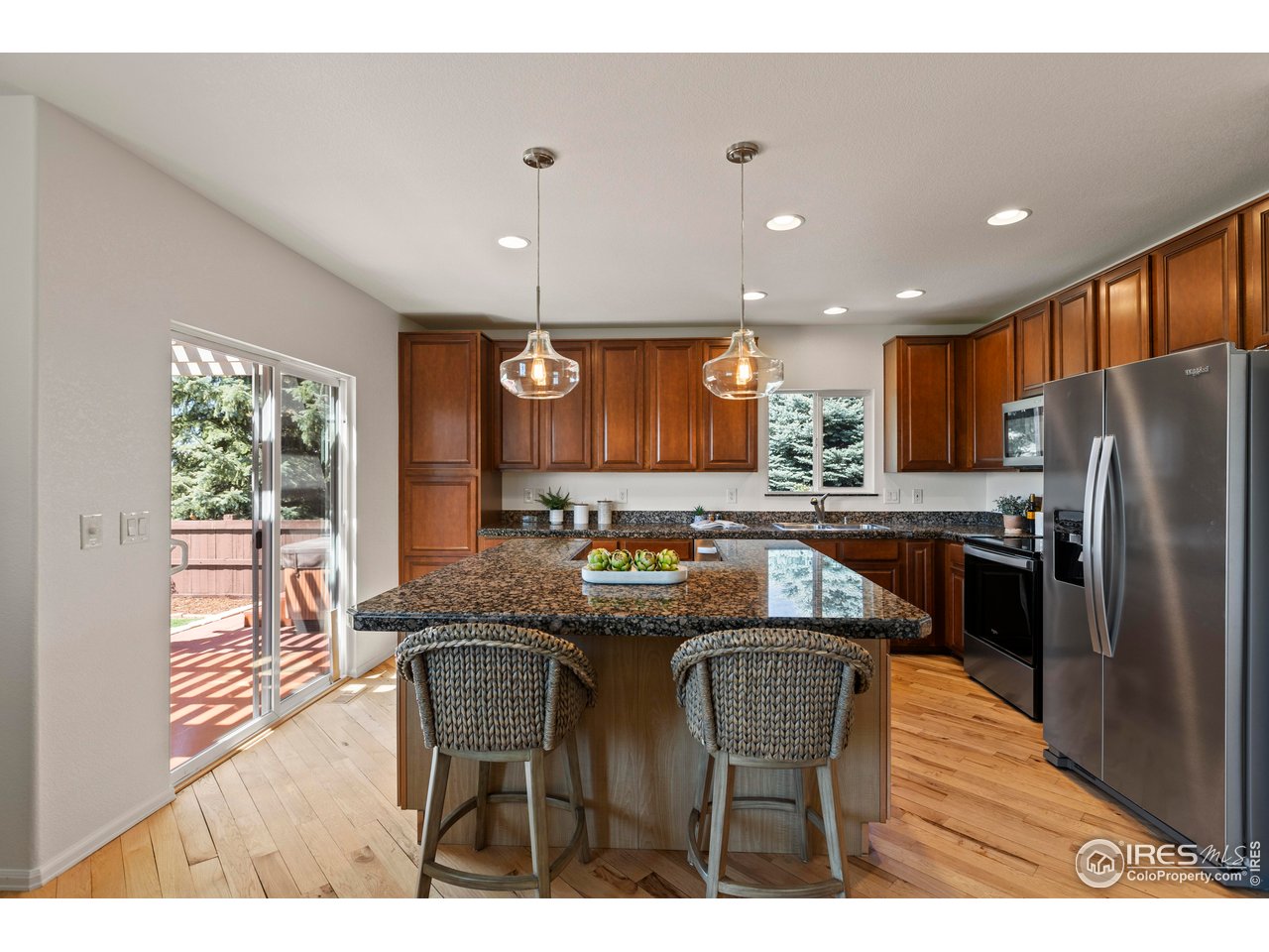 6117 Gold Dust Road Timnath, CO 80547 - Photo 13 of 43 a kitchen with stainless steel appliances granite countertop a table chairs sink refrigerator and microwave