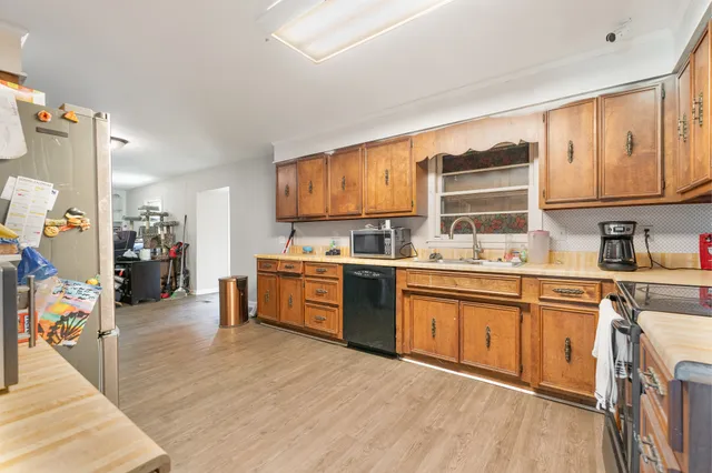 a kitchen with stainless steel appliances kitchen island granite countertop a sink cabinets and wooden floor