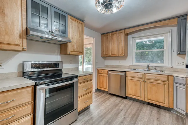 a kitchen with cabinets wooden floor and stainless steel appliances