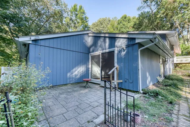 a backyard of a house with a small barn plants and large tree