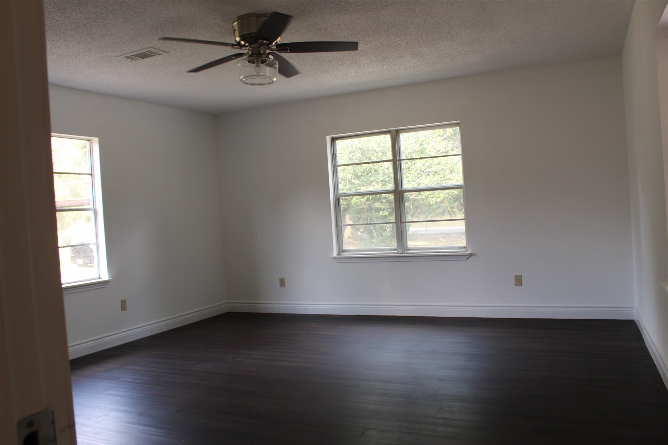 14040 FM 1484 Road Conroe, TX 77303 - Photo 21 of 47 an empty room with wooden floor chandelier fan and windows