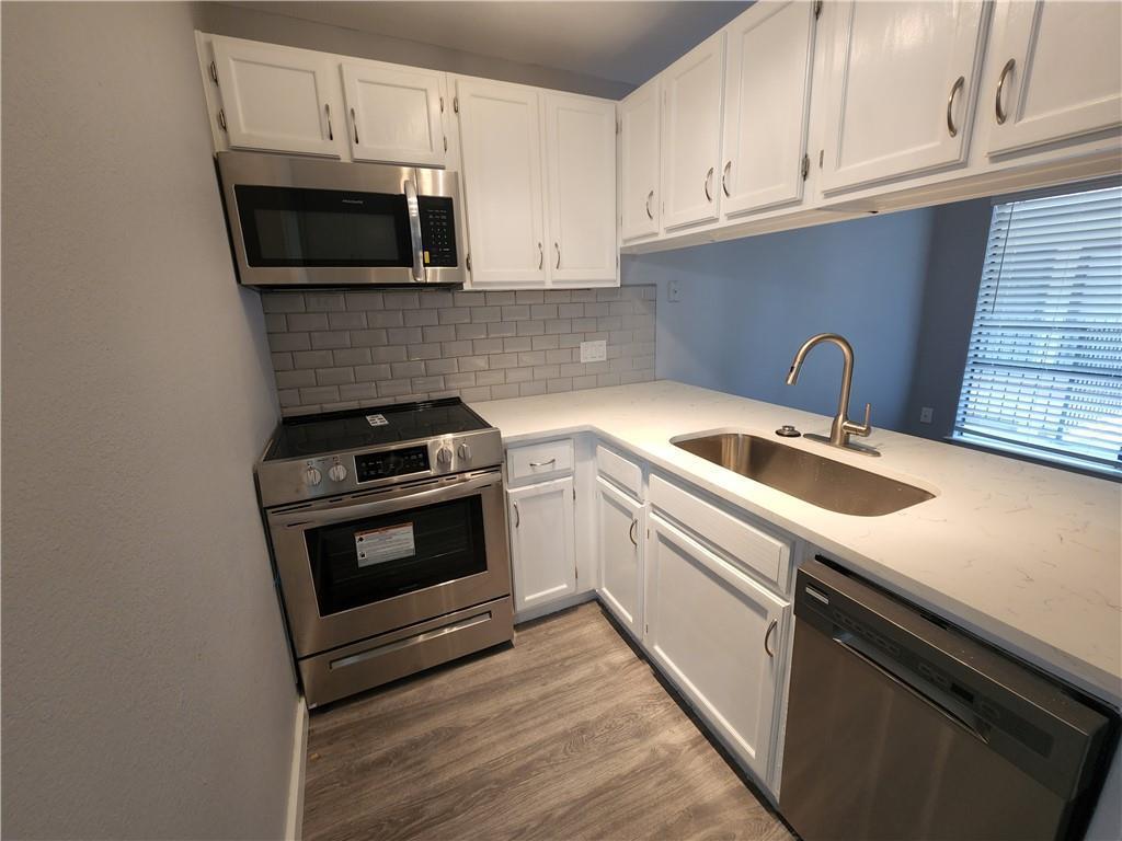 2815 Rio Grande Street, Unit 202 Austin, TX 78705 - Photo 2 of 11 a kitchen with granite countertop a sink dishwasher microwave stove and cabinets with wooden floor