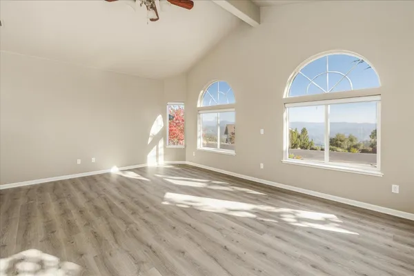 a view of empty room with window and wooden floor