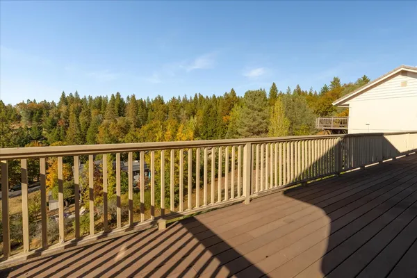 a view of a balcony with wooden floor and trees in the background