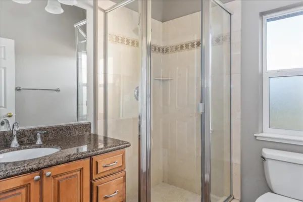 a bathroom with a granite countertop sink a mirror and a shower