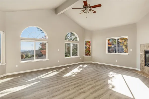 a view of an empty room with a window and wooden floor
