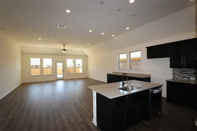 a large kitchen with stainless steel appliances kitchen island a large counter top and a wooden floors