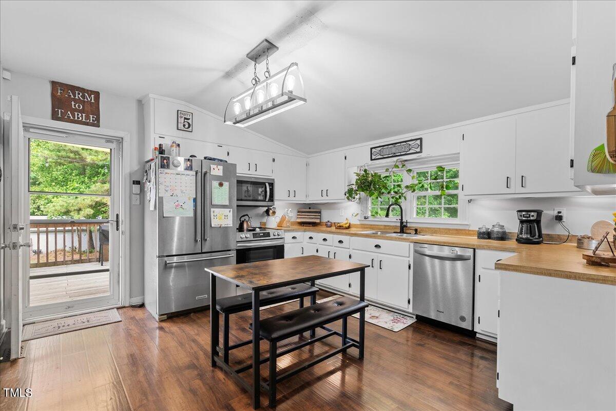 3151 Brogden Road Stem, NC 27581 - Photo 8 of 58 a kitchen with stainless steel appliances a stove a refrigerator a sink dishwasher and a dining table with wooden floor