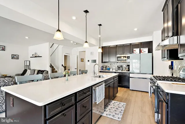 a kitchen with a sink a counter top space stainless steel appliances and a center island