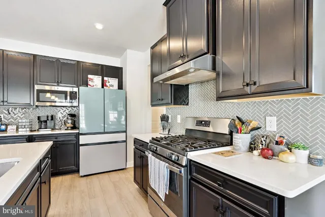 a kitchen with stainless steel appliances granite countertop a stove refrigerator and cabinets