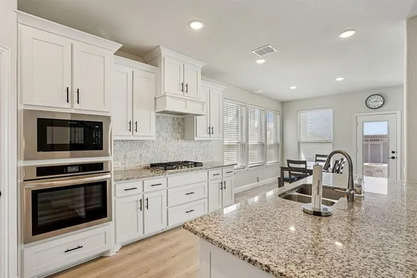 a kitchen with granite countertop a stove sink and cabinets
