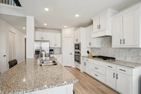 a large kitchen with granite countertop a white cabinets and stainless steel appliances