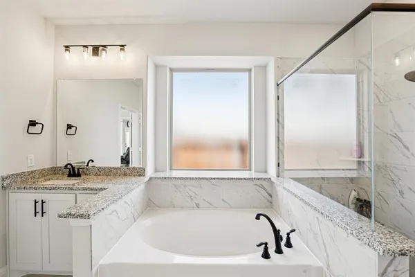 a bathroom with a granite countertop tub sink and mirror
