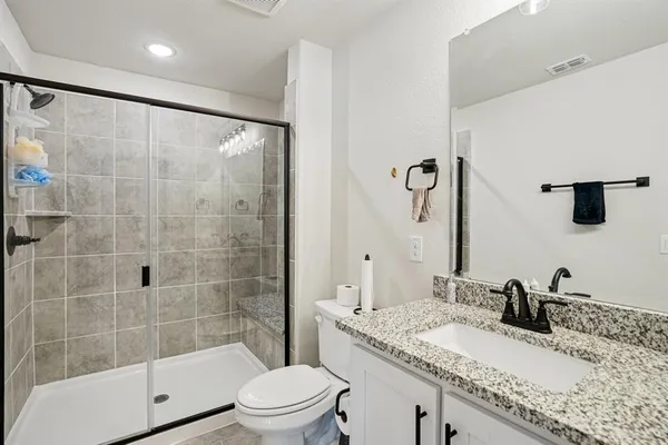 a bathroom with a granite countertop sink a toilet and shower