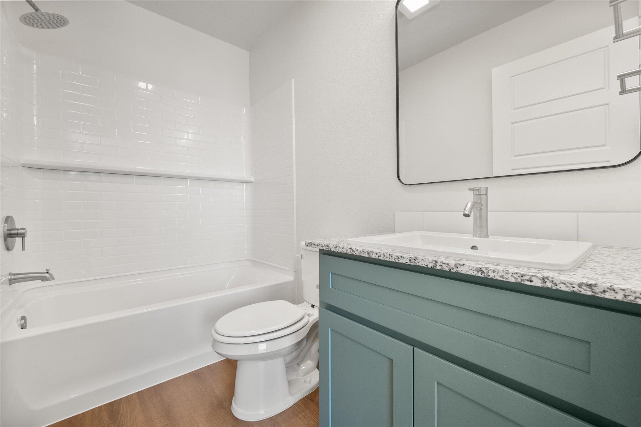 5518 Smith Street Lubbock, TX 79416 - Photo 17 of 22 a bathroom with a granite countertop sink a toilet and bathtub
