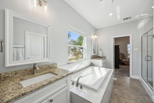 a bathroom with a granite countertop sink and mirror with bathtub