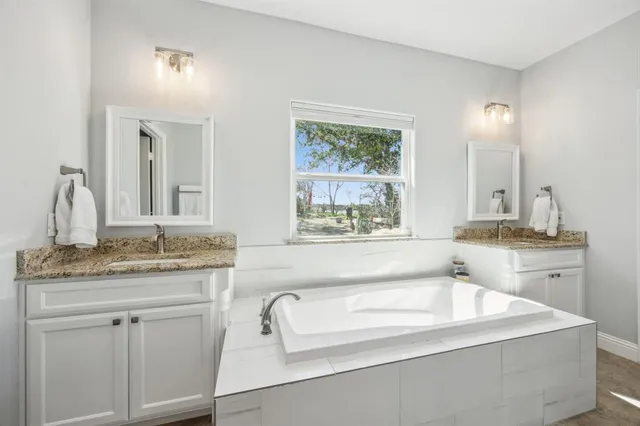 a bathroom with a granite countertop sink and a bathtub