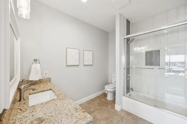 a bathroom with a granite countertop sink a toilet and shower