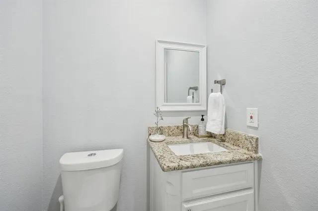 a bathroom with a granite countertop sink and a toilet