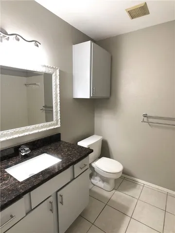 a bathroom with a granite countertop toilet and a sink