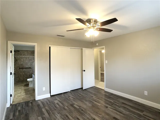 an empty room with wooden floor fan and windows