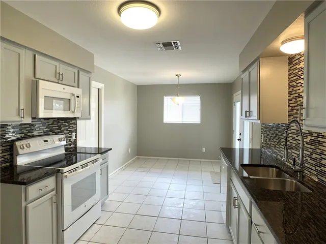 a kitchen with granite countertop a sink stove and cabinets