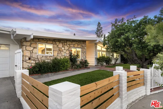 a view of a patio with couches plants and large tree