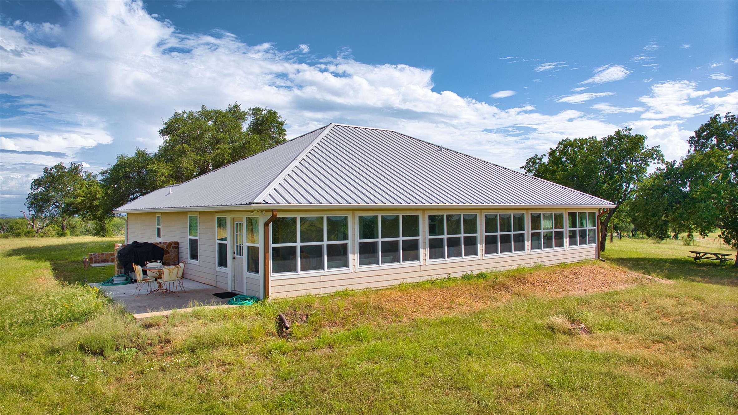 12119 Highway 29 Llano, TX 78643 - Photo 13 of 40 Back of property with a patio area, a yard, and a metal roof