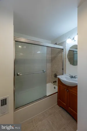 a bathroom with a granite countertop sink a mirror and shower