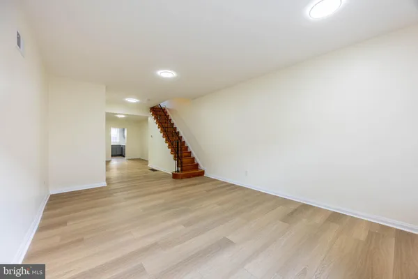 a view of an empty room with wooden floor and stairs