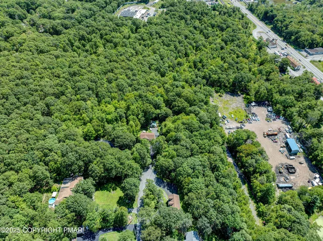an aerial view of residential house with outdoor space and trees all around