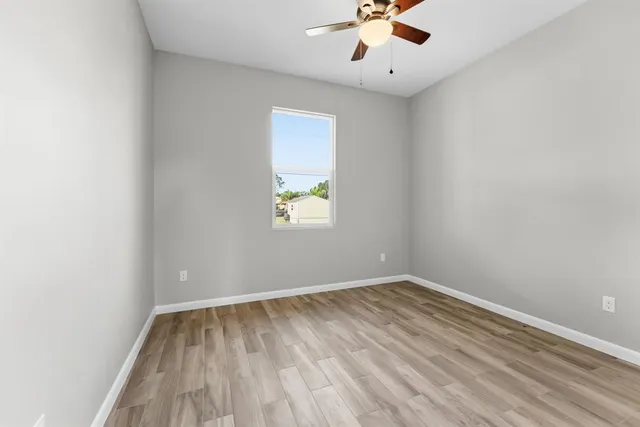 an empty room with a window and a ceiling fan