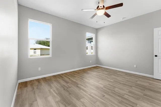 an empty room with windows and fan