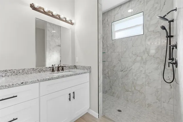 a bathroom with a granite countertop sink a shower and a mirror