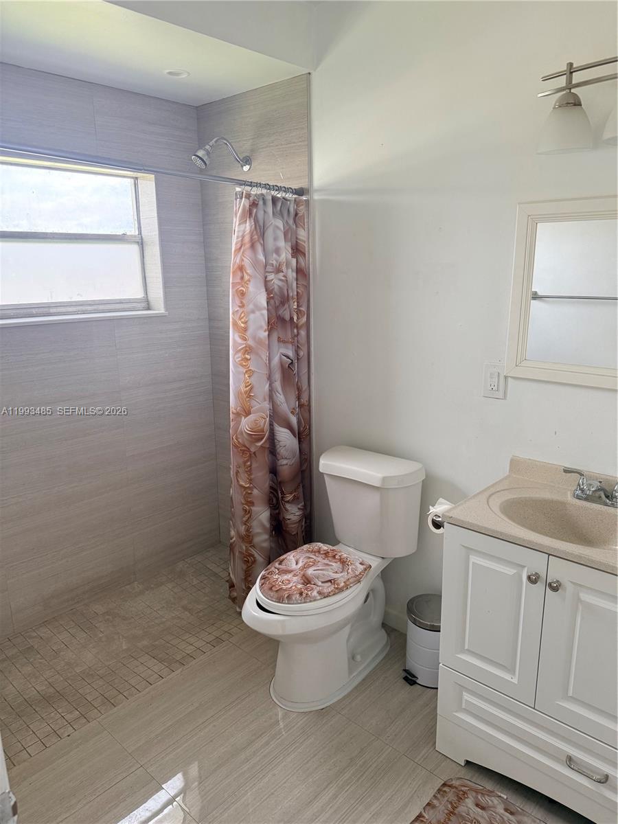 26468 Southwest 123rd Place Homestead, FL 33032 - Photo 14 of 33 a bathroom with a granite countertop toilet a sink and a shower