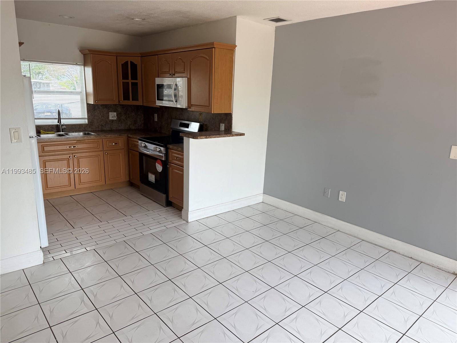 26468 Southwest 123rd Place Homestead, FL 33032 - Photo 10 of 33 a kitchen with granite countertop white cabinets and black appliances