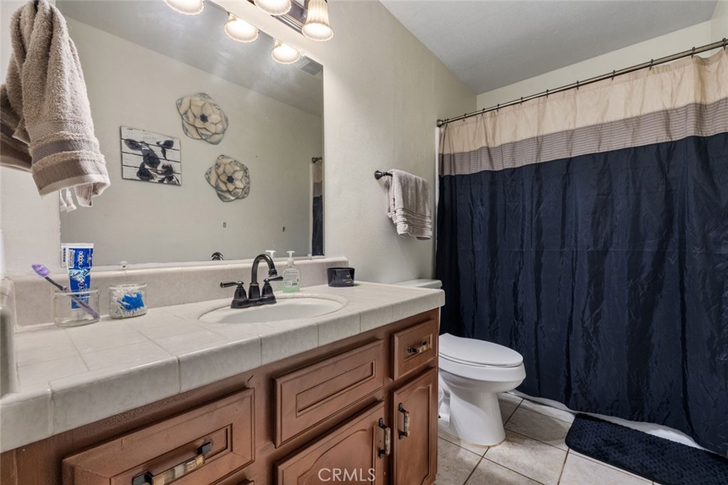 9068 Montero Road Valley Springs, CA 95252 - Photo 24 of 50 a bathroom with a granite countertop sink a toilet and a mirror